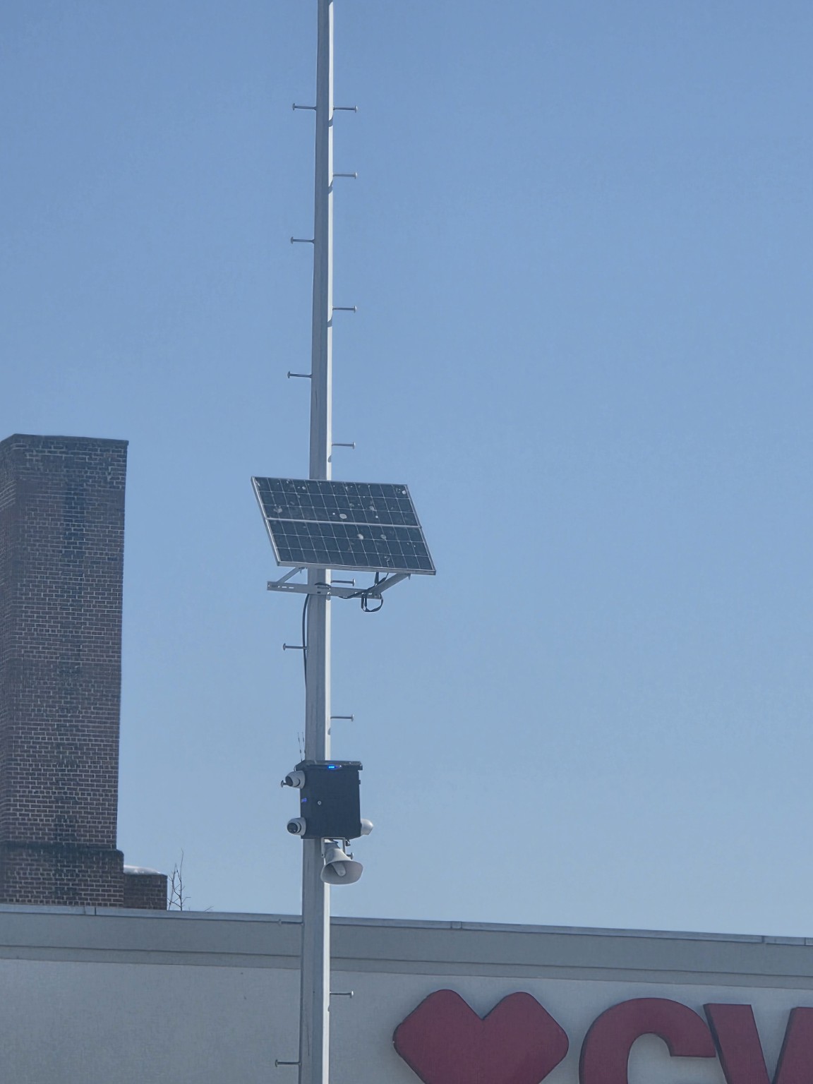 Solar-powered active deterrence camera system installed on a tall commercial property pole