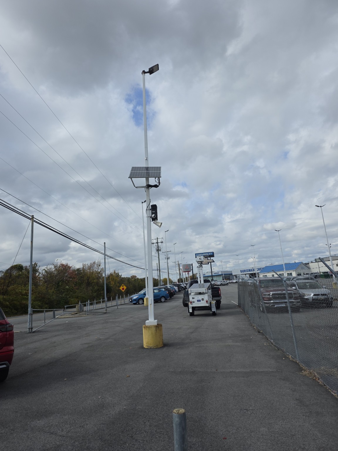 Wide view of a solar-powered surveillance system covering a dealership parking lot